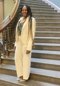 A woman wearing a white suit poses on a staircase